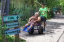 Voluntário transportando idosa em uma cadeira de rodas pelo litoral