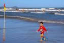 Criança na beira da praia com mar ao fundo