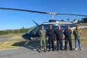 Agentes fiscalizadores posando para foto com um helicóptero ao fundo