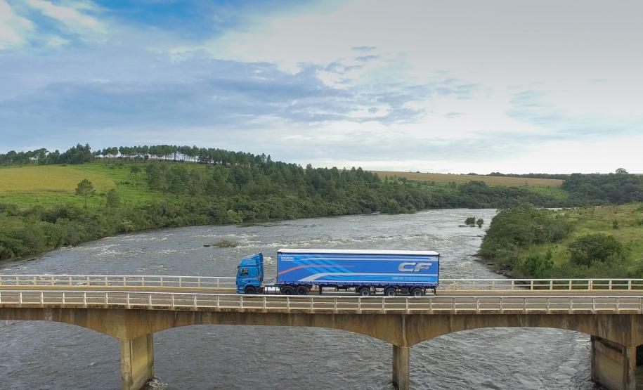 Caminhão da DAF passando por uma ponte com a natureza paranaense ao fundo